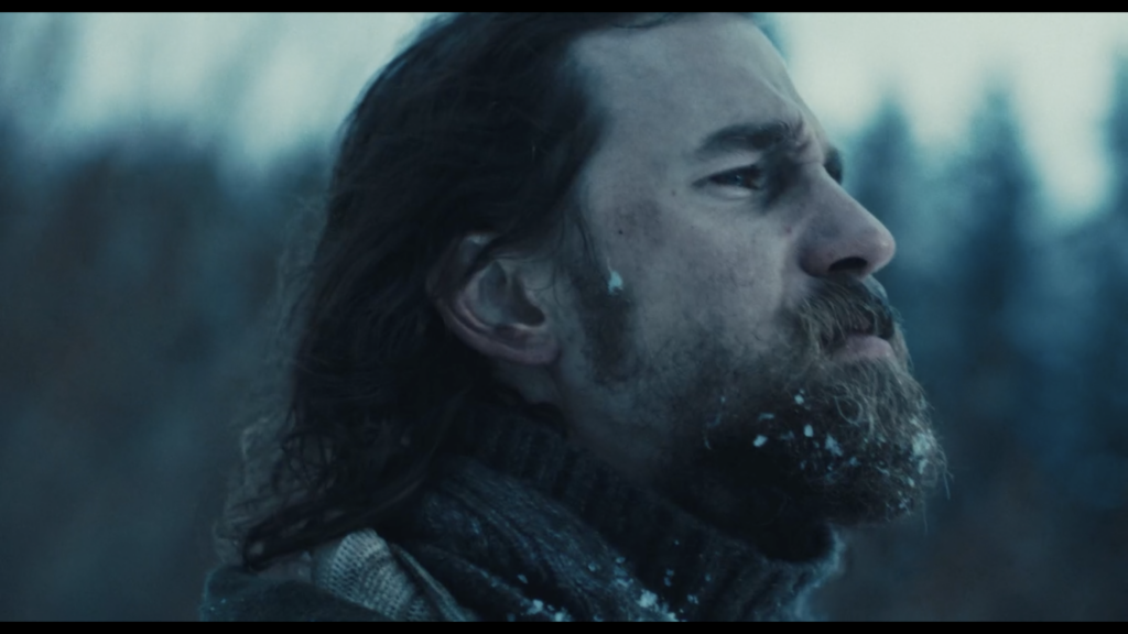 Man in snowy setting looks right.